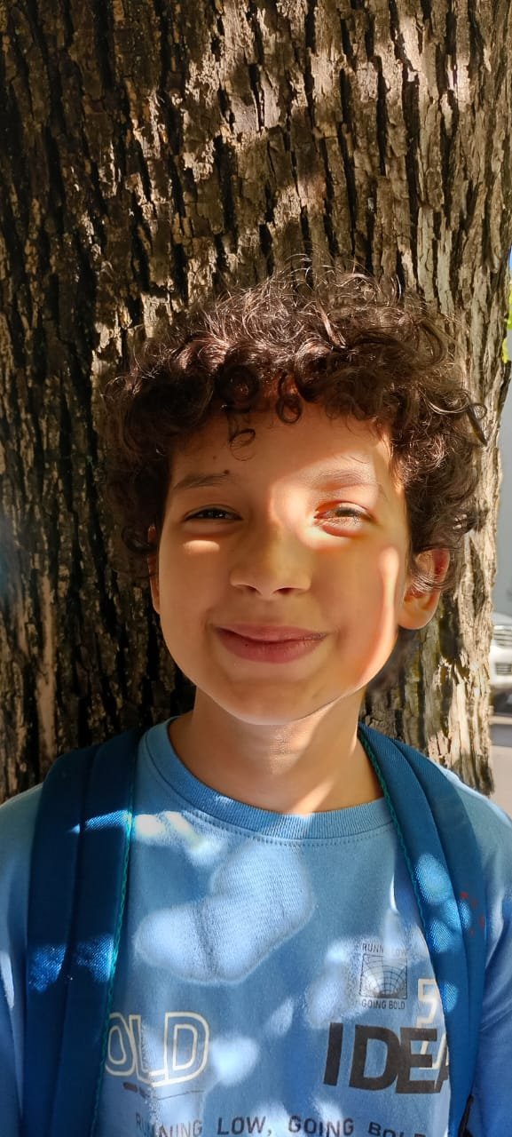 Simón sonriendo bajo un árbol